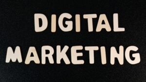 The words “DIGITAL MARKETING” are spelled out in large, light-colored wooden letters on a black textured background—perfect imagery for a marketing agency specializing in web site design and digital marketing.