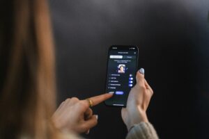 A person holds a smartphone and adjusts settings on a video call interface, with toggle options for audio, video, background music, language, and web site design visible on the screen.