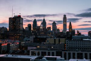 Philadelphia city skyline at sunset, featuring tall buildings and the iconic clock tower of City Hall—a perfect backdrop for digital marketing or web site design inspiration, with blue, pink, and orange hues lighting up the sky.
