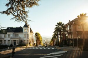 A sunlit street in a hilly neighborhood with palm trees, historic houses, a Buena Vista Park sign, and a person crossing the intersection—an inviting scene ideal for a marketing agency’s digital marketing or web site design inspiration.