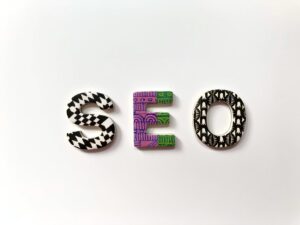 The letters S, E, and O are decorated with black-and-white and purple-green patterns, arranged side by side on a plain white background, representing key elements of digital marketing and web site design.