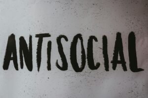 The word ANTISOCIAL is written in large, bold, black, hand-drawn letters on a white background with scattered black specks—perfect inspiration for a marketing agency focused on edgy digital marketing or web site design.