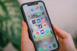 A person holding a smartphone displays a folder labeled Réseaux sociaux with social media apps like LinkedIn and TikTok—essential tools for any marketing agency specializing in Social Media Management.