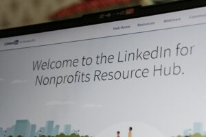A laptop screen displays the LinkedIn for Nonprofits Resource Hub webpage, highlighting resources for marketing agency teams and social media management with the text, Welcome to the LinkedIn for Nonprofits Resource Hub.