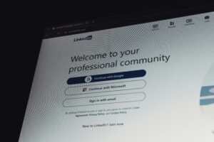 A computer screen displays the LinkedIn login page with options to continue using Google, Microsoft, or email. Ideal for a marketing agency, the page welcomes users to their professional community and offers seamless access for networking and growth.