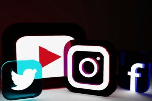 Four illuminated 3D social media icons—YouTube, Instagram, Twitter, and Facebook—shine against a dark background, perfect for showcasing Web site design or highlighting Social Media Management in your digital marketing strategy.