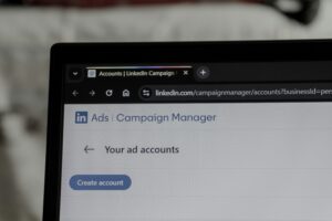 A computer screen displays the LinkedIn Campaign Manager page, showing Your ad accounts and a Create account button under the Ads section—ideal for a marketing agency specializing in social media management.