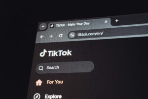 A computer screen displays the TikTok website in dark mode, highlighting the search bar, For You, and Explore options—perfect for digital marketing or a social media management team at a marketing agency.