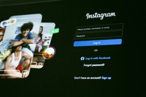 Instagram login screen displayed on a dark background, with fields for phone number, username, or email, and password. On the left, overlapping images of smiling people and colorful icons hint at vibrant digital marketing and social media management.