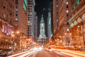 Night view of a busy city street with light trails from cars, tall buildings on both sides, and a large, illuminated historic building with a clock tower—an inspiring scene for any marketing agency or digital marketing campaign.